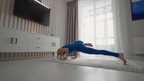 A-young-woman-in-isolation-does-yoga-at-home-on-a-mat-in-her-apartment